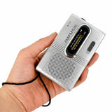 Indin portable AM FM pocket radio in silver held in hand with FM/AM tuning dial