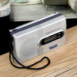 Indin portable AM FM pocket radio in silver with easy-to-read dial and wrist strap for on-the-go listening